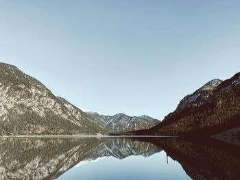 Scenic view of lake and mountains against clear blue sky