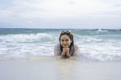 Portrait of young woman swimming in sea against sky