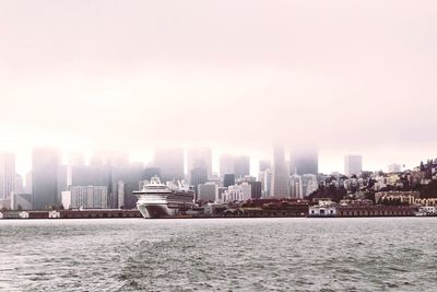 Sea by buildings in city against sky