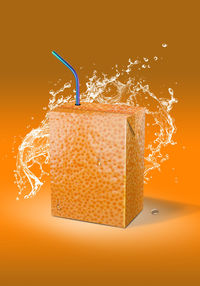 Close-up of yellow water splashing against orange background