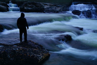 Rear view of man looking at waterfall