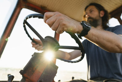 Mature farmer driving tractor on sunny day