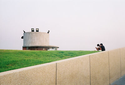 People sitting on field against sky