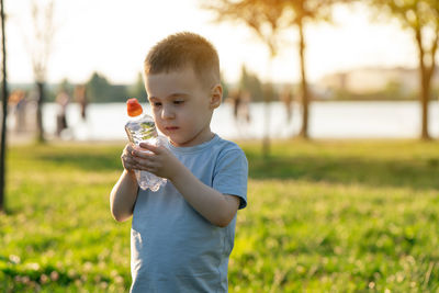 Young woman drinking water while sitting on field