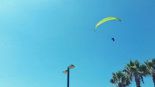 Low angle view of person paragliding against clear blue sky