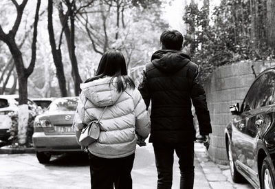 Rear view of people walking on road against trees