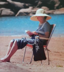 Full length of senior man sitting on floor by sea