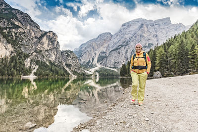 Man standing on lake by mountains against sky