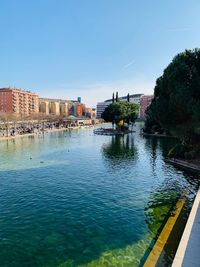 River by buildings against clear blue sky