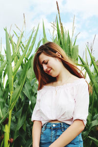 Beautiful young woman standing against plants