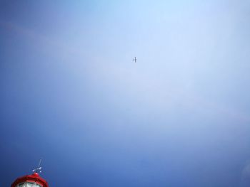 Low angle view of airplane flying against clear blue sky