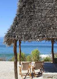 Deck chairs on beach against clear sky