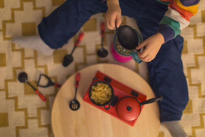 Low section of boy cooking food while playing with toys at home