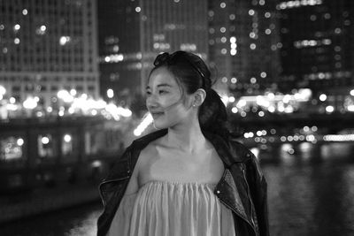 Portrait of woman on illuminated street in city at night