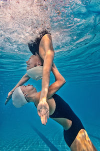 Side view of female swimmers synchronized swimming in pool