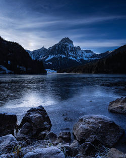 Scenic view of lake by snowcapped mountains against sky