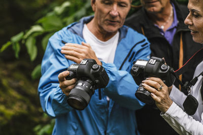 Senior man showing camera to female instructor during photography course