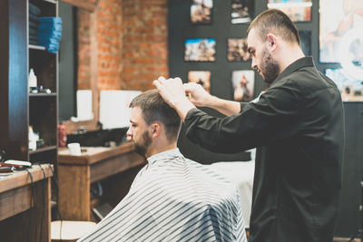 Side view of barber cutting customer hair