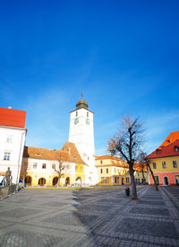 Street amidst buildings against blue sky