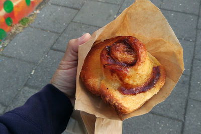 Cropped image of hand holding food in paper bag