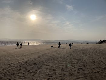 People at beach against sky during sunset