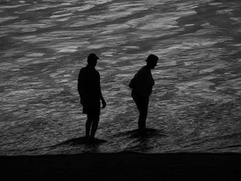 Silhouette people standing on beach