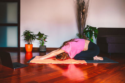 Young woman doing physical exercise in the living room of her home