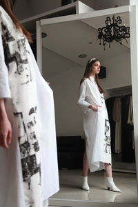 Side view of girl standing by mirror at home