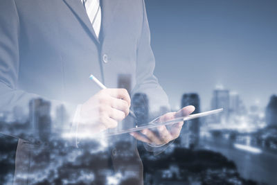 Double exposure image of businessman using digital tablet and illuminated city
