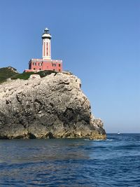 Lighthouse by sea against sky