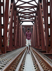 Rear view of person walking on railroad tracks