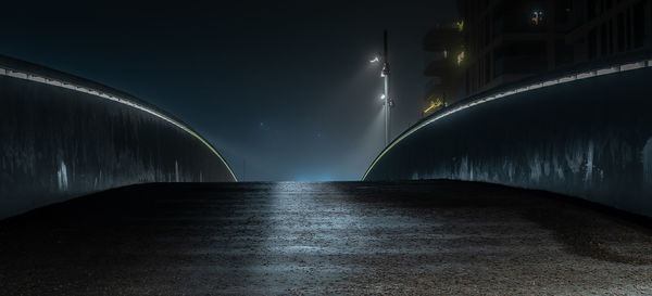 Illuminated bridge over street against sky at night