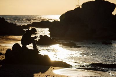 Silhouette people on beach against sky during sunset