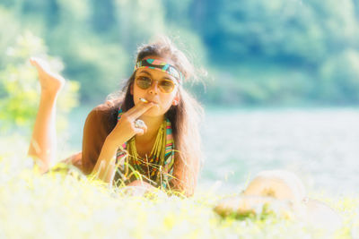 Portrait of woman wearing sunglasses smoking cigarette on beach