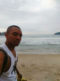 Mid adult man standing on beach against sky