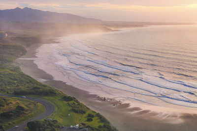 High angle view of land and sea against sky during sunset