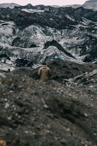 Rear view of man standing amidst rocky mountains