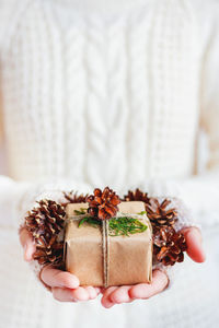 Woman holds present in craft paper with pine cones. diy christmas, new year, st. valentine day gift.