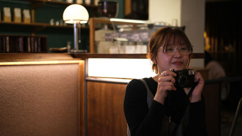 Portrait of young woman looking away while standing in cafe