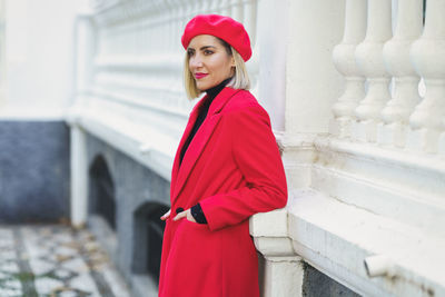 Portrait of young woman standing against building