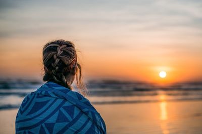 Rear view of woman against sea during sunset