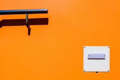 Close-up of railing on orange wall