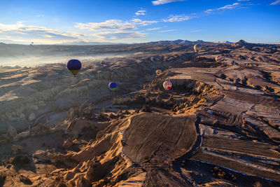 Hot air balloons flying over cappadocia against sky