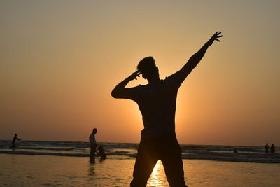 Silhouette of man on beach against sky during sunset