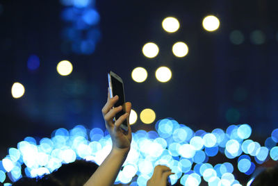 Close-up of hand holding illuminated smart phone at night