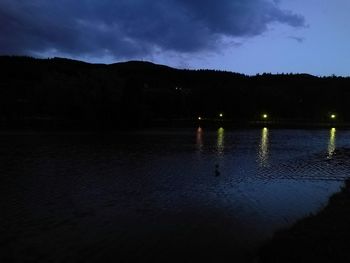 Reflection of illuminated trees on water at night