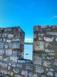 Wall by sea against clear blue sky