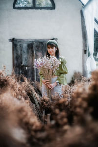 Full length of woman standing by flowering plants