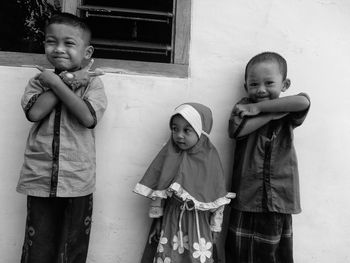 Portrait of cute siblings standing against wall