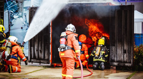 Rear view of people standing against fire